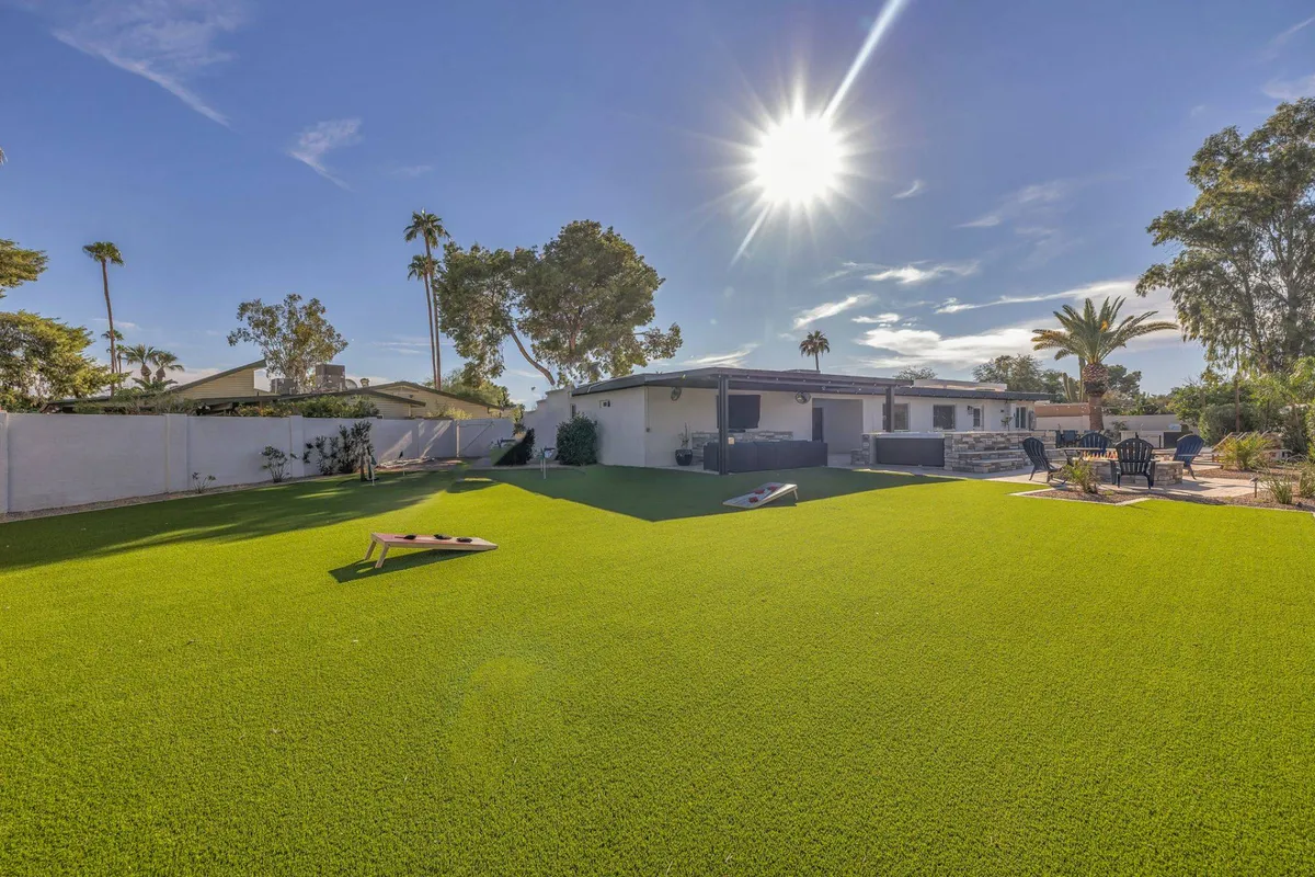 A cheerful exterior scene featuring artificial turf, lawn games in progress, outdoor seating, and plenty of sunlight. The setup conveys a sense of active outdoor fun and relaxed gatherings, ideal for both kids and adults.