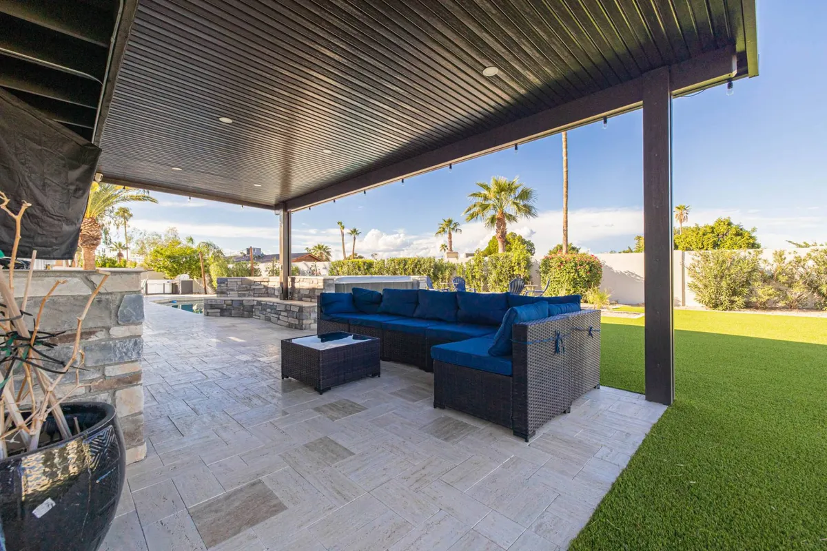 Outdoor seating area set against a decorative stone wall, surrounded by a lush green lawn and ample space for entertaining or quiet reflection. The setting is both intimate and inviting, suitable for enjoying Arizona’s beautiful weather.